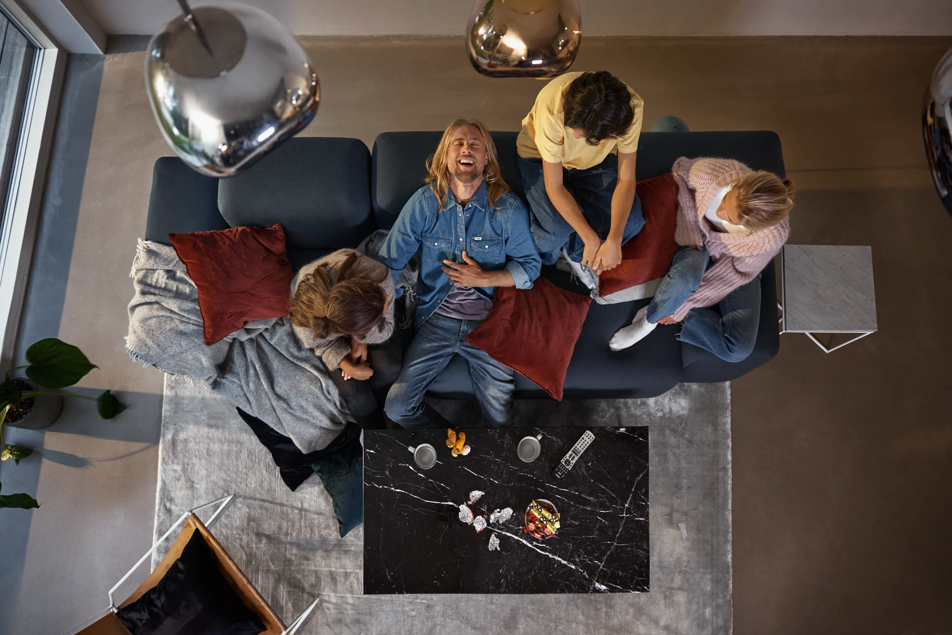 Vänner tittar på tv tillsammans i soffan och en viker sig av skratt. Streama massor av underhållning du också, med något av våra bästa streamingpaket!