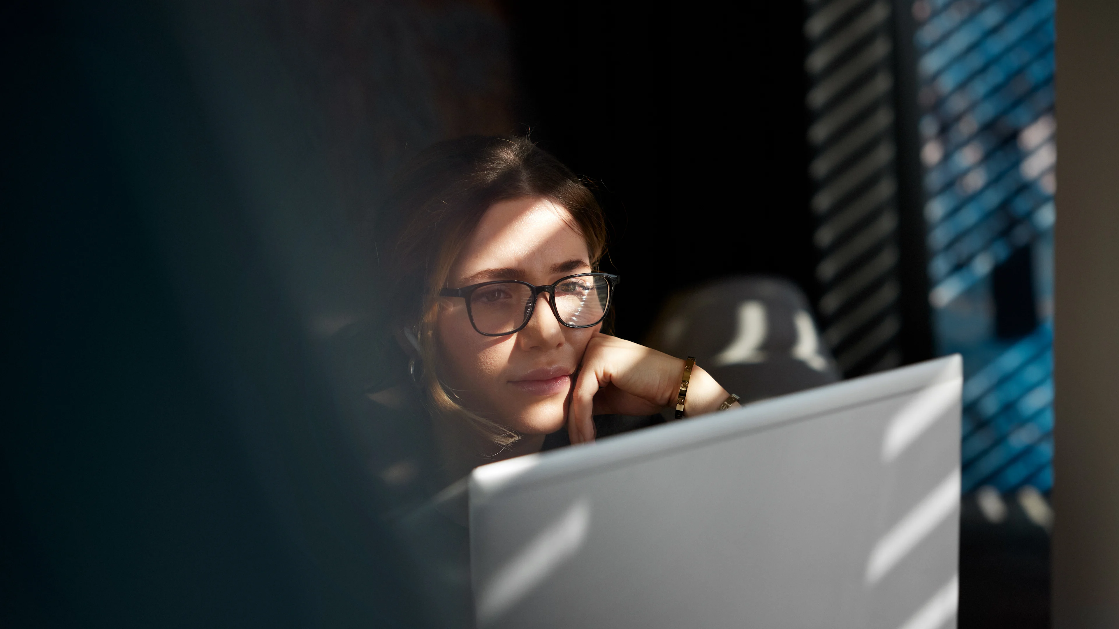 Kvinna som betraktar dataskärm med handen mot hakan.