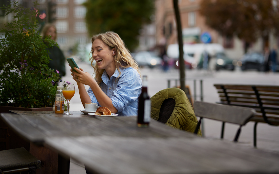 Kvinna arbetar med mobil i Telias nät på café