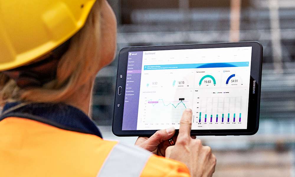 Kvinna med hjälm använder surfplatta på arbetsplats.