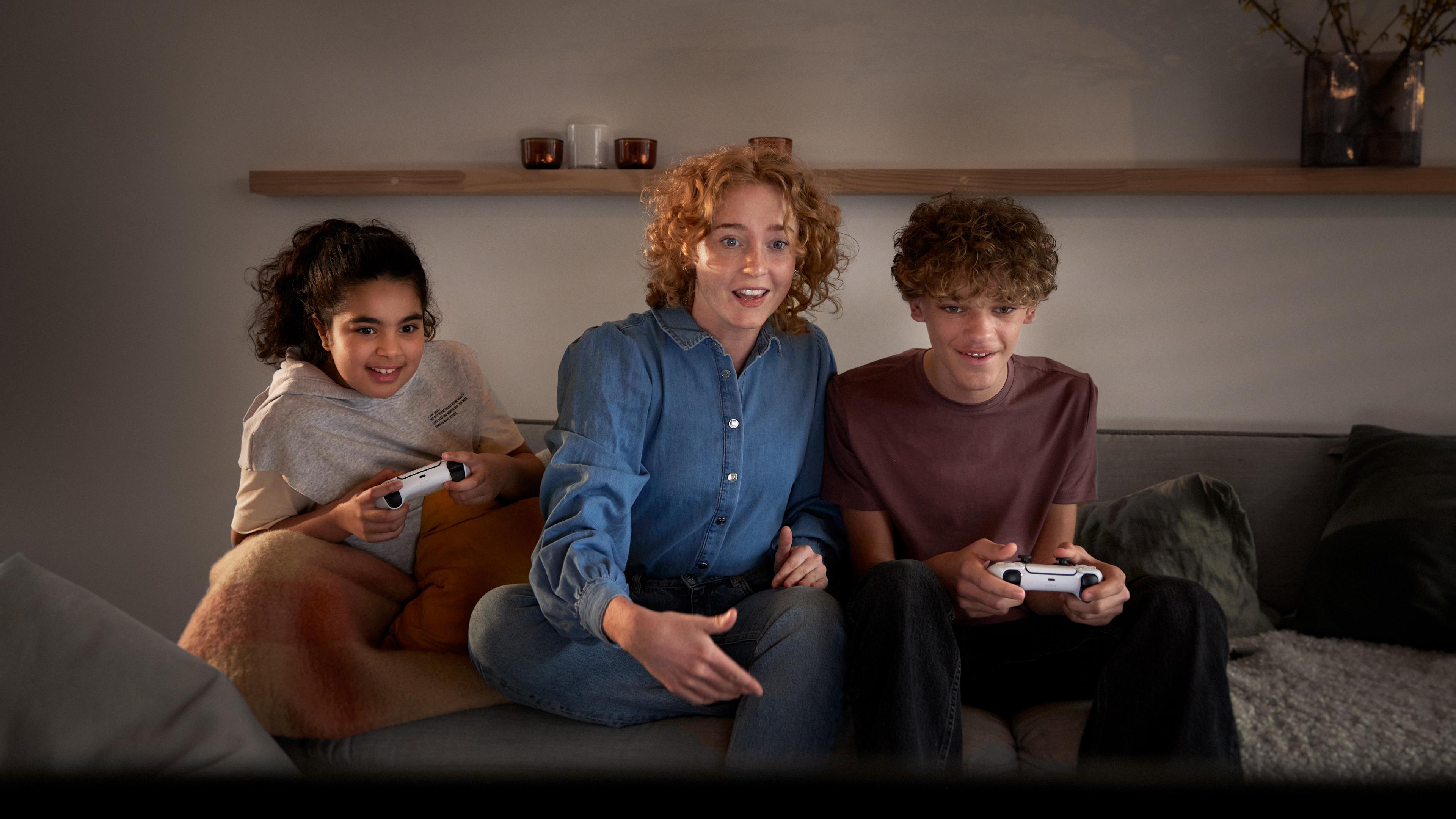 Kvinna och två barn spelar tv-spel tillsammans.