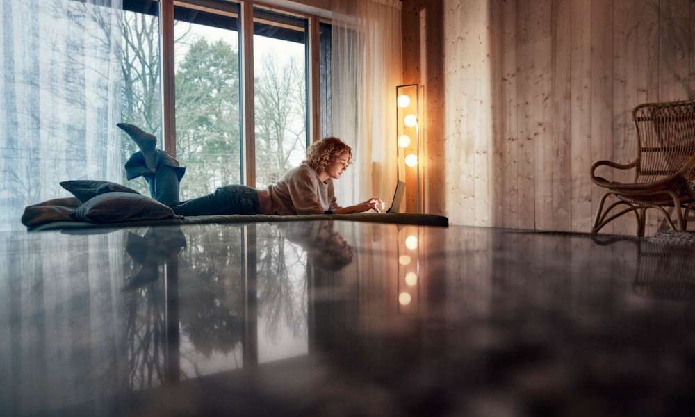 Kvinna ligger på golvet med en laptop-dator.