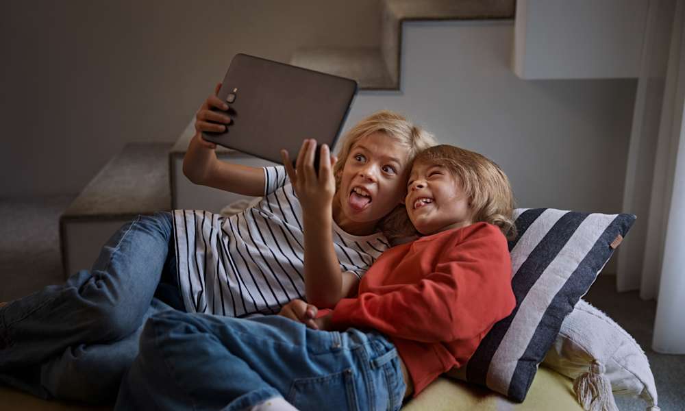 Två barn leker med en surfplatta.