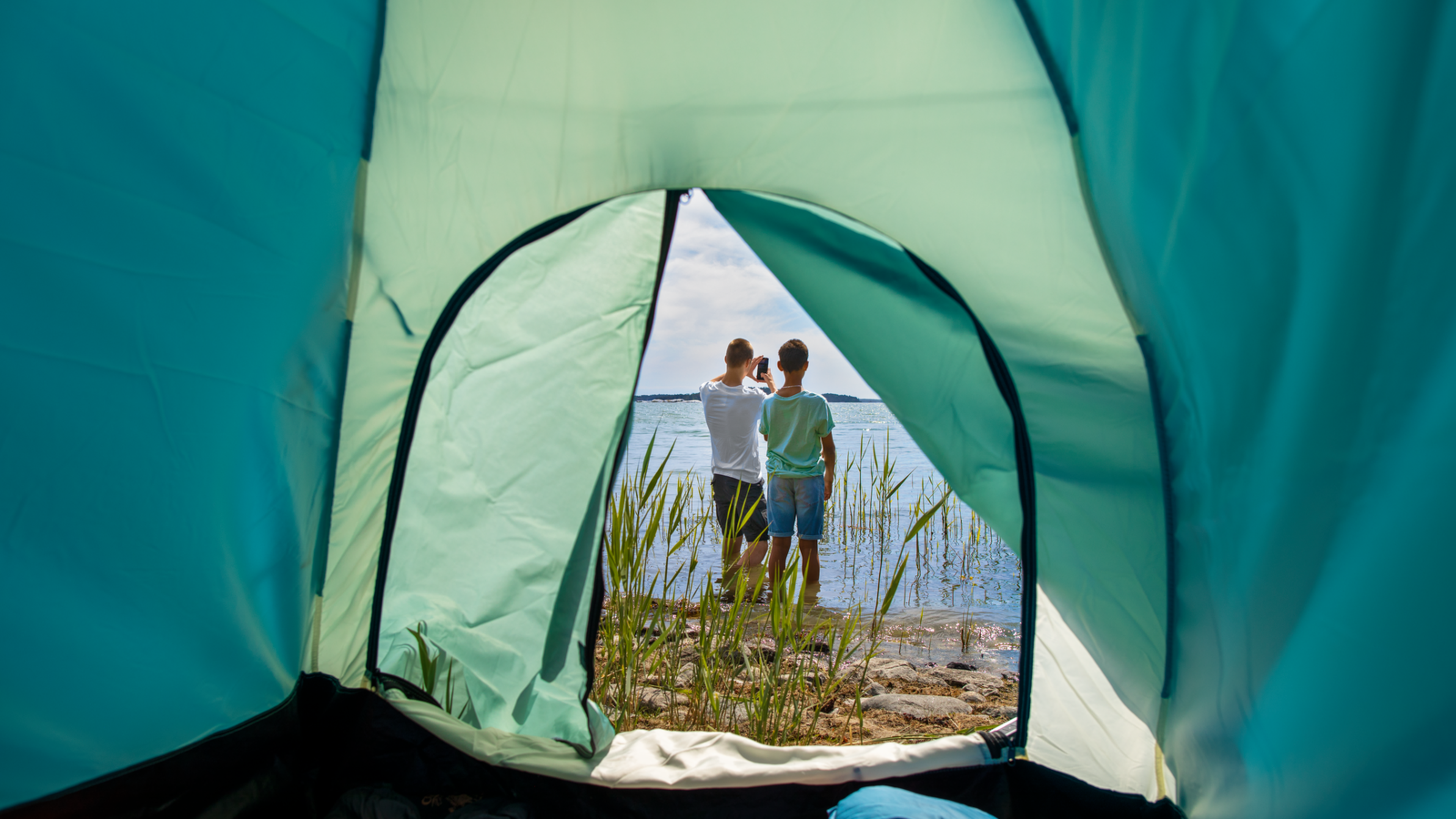 Två tonårskillar med mobil vid stranden.