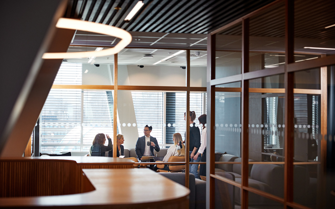 Personer som samtalar bakom glasvägg i ett konferensrum.