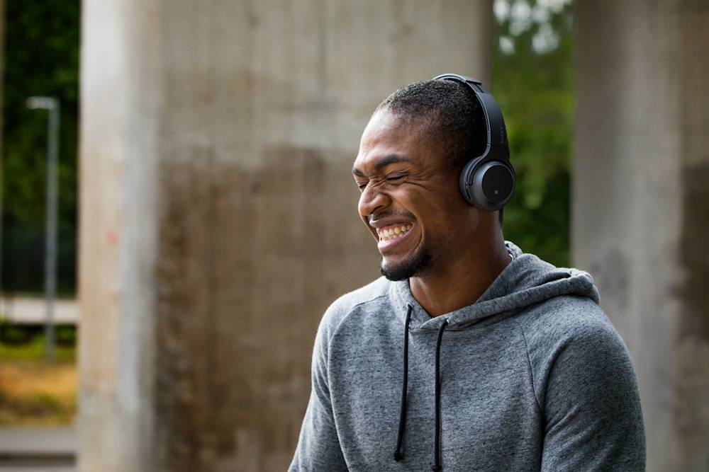 Leende man som lyssnar i hörlurar