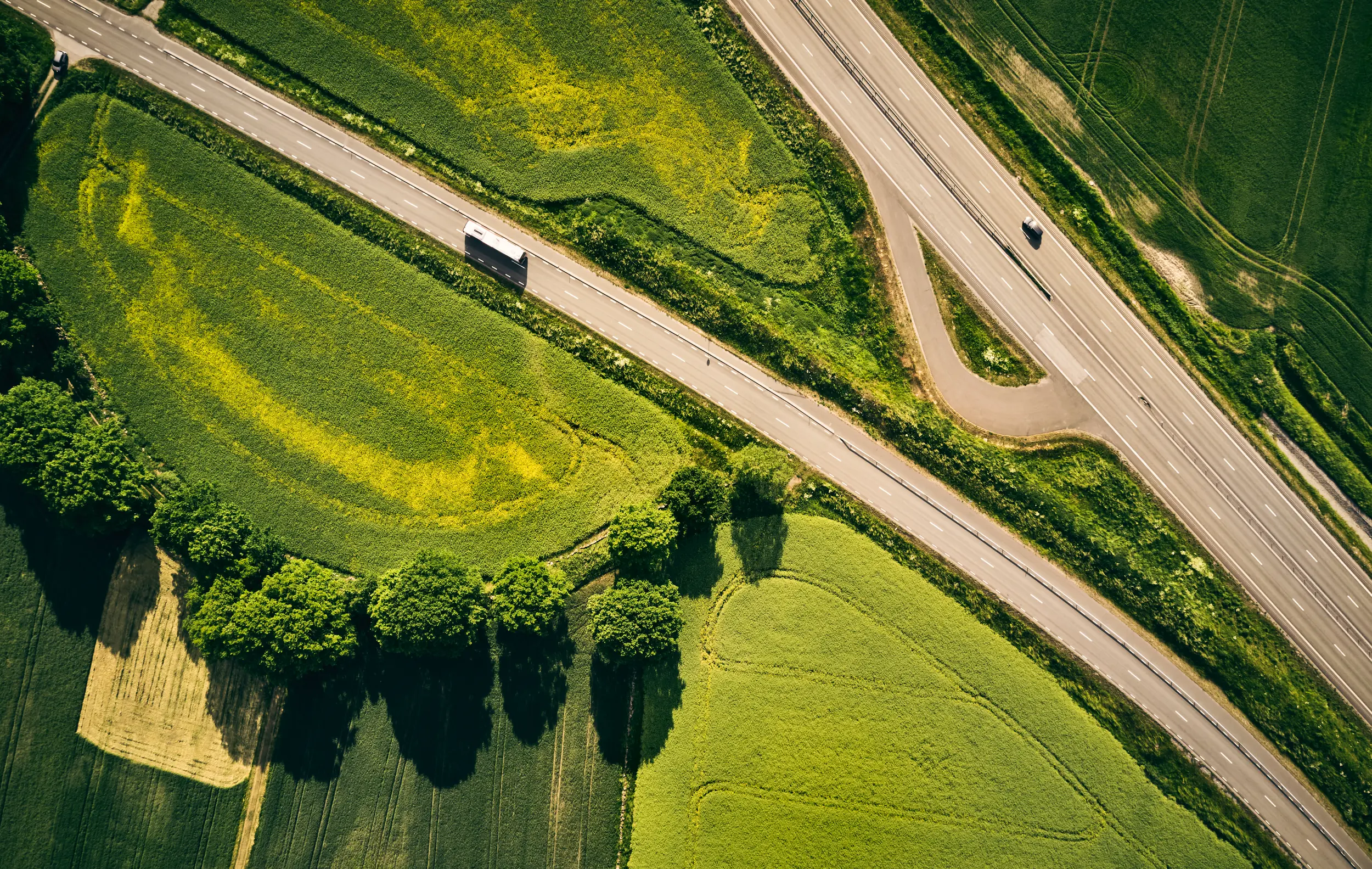 Flygfoto över väg med bil på och gröna omgivningar