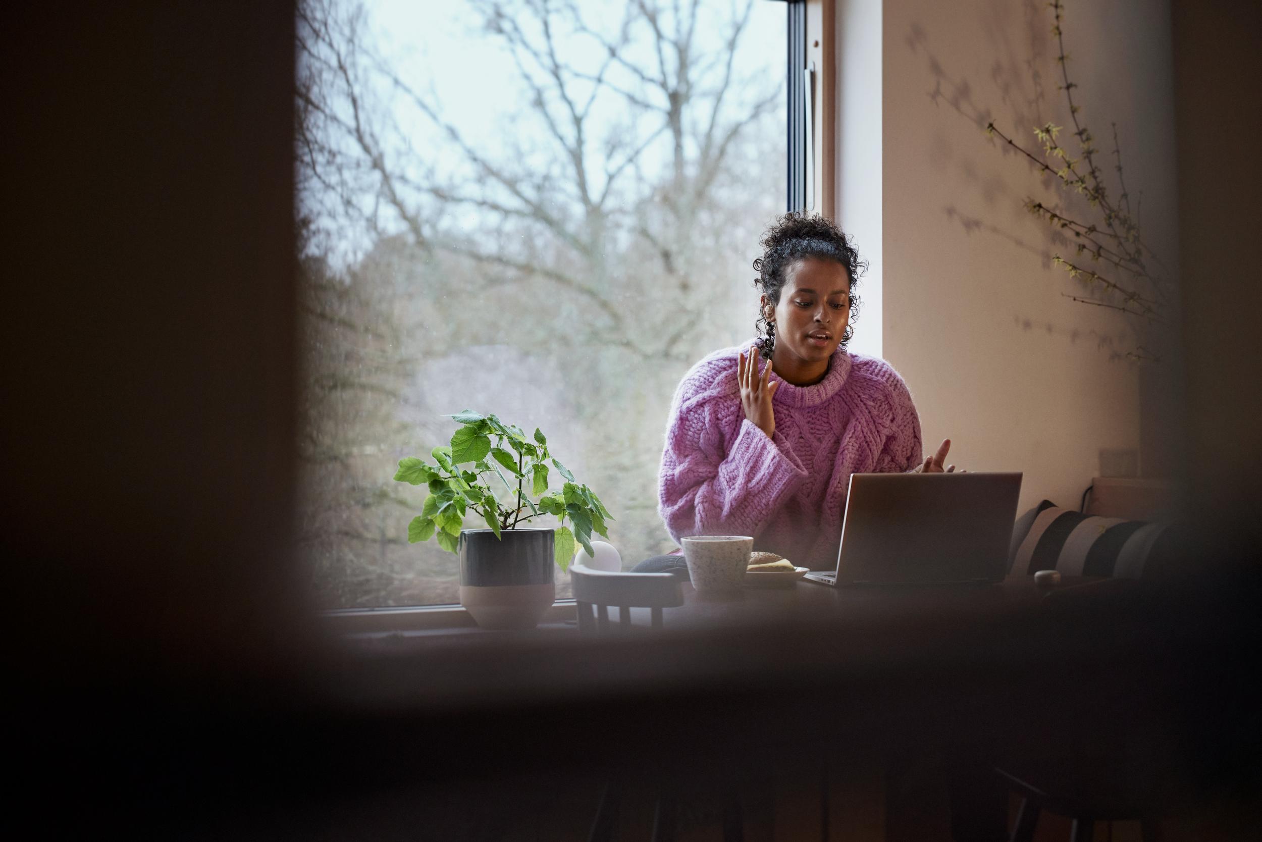 Kvinna arbetar vid laptop i hemmamiljö.