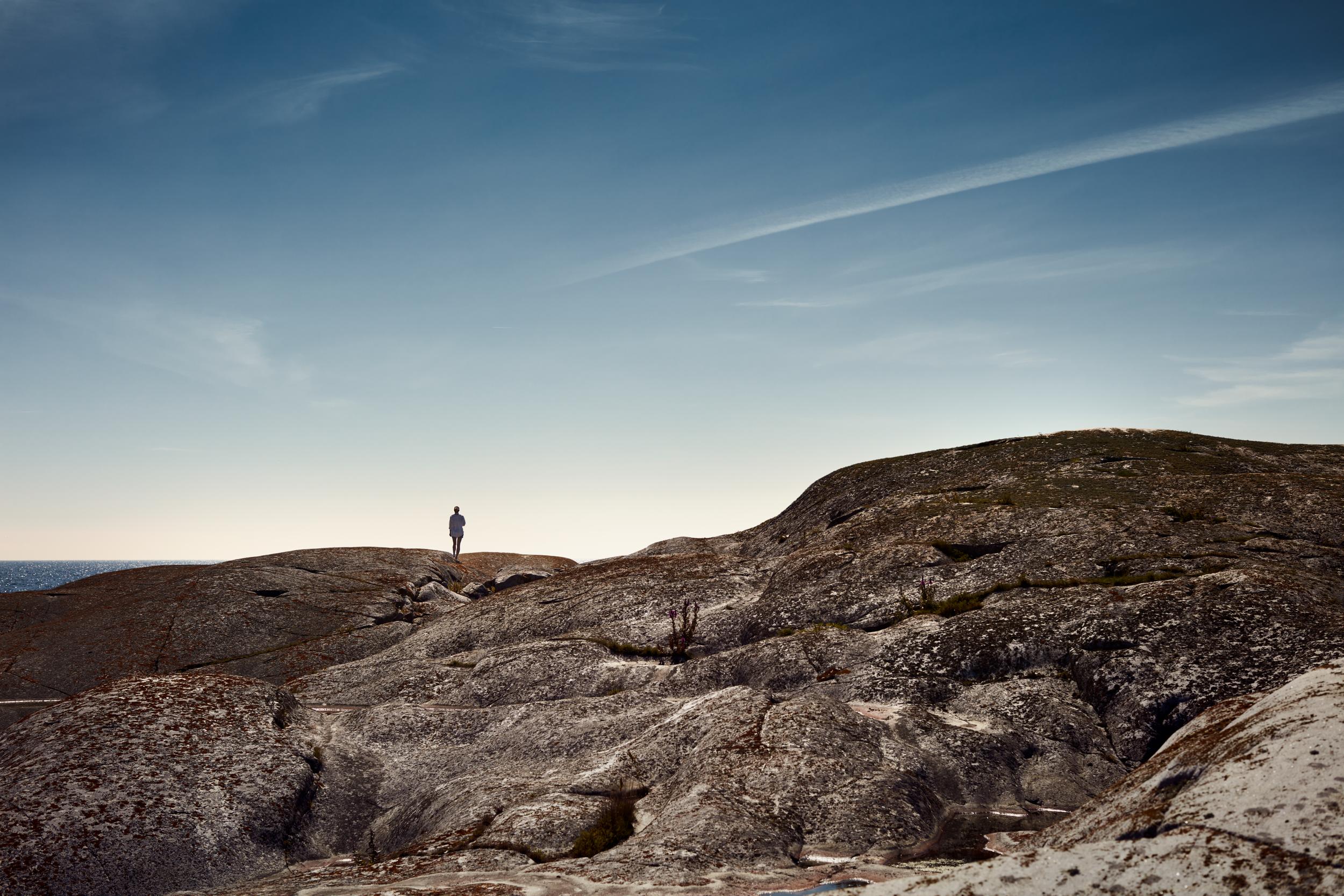 Miljöbild av person på klippor i havsbandet.