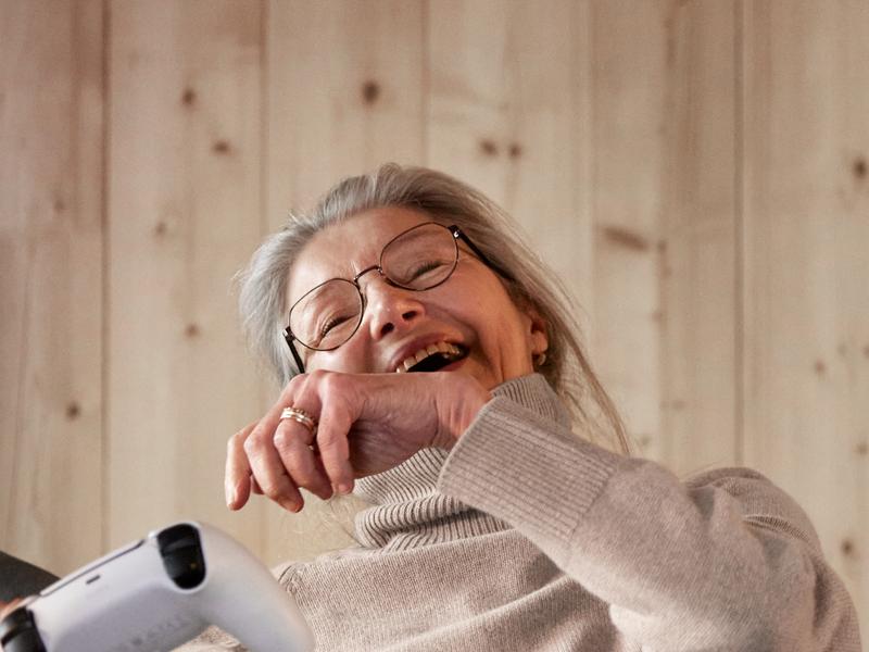 Närbild på glad pensionär som gejmar i soffa